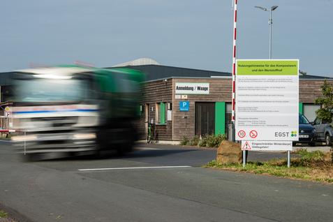 Lkw fährt an einem Containerzentrum mit Anmeldeschalter und Hinweistafel vorbei.