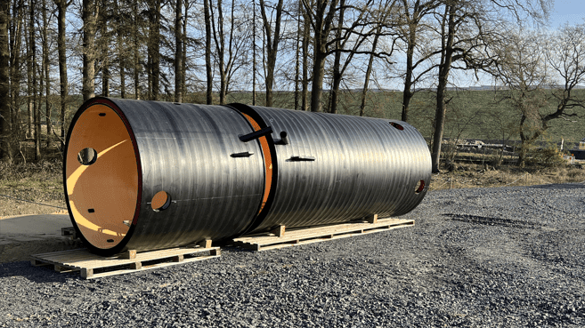 Große schwarze Rollen lagern auf einem Schotterplatz.