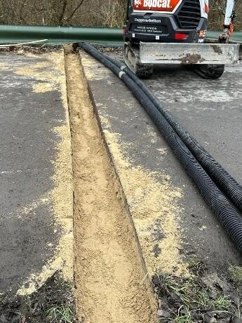 Eine Straße wurde mit einem Schlitz aufgebrochen, um einen Querungstunnel für Amphibien zu bauen.
